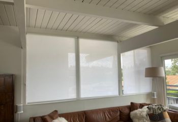 Custom roller shades installed in the living room of a Mission Viejo condo, complementing the leather sofa and modern floor lamp.